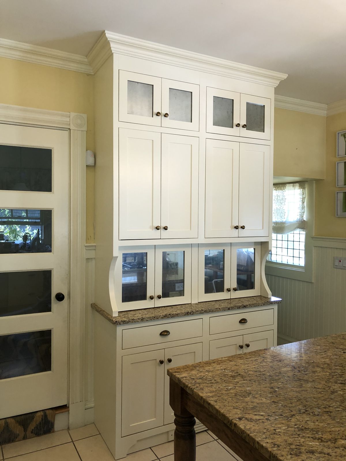 White glass-front cabinetry with granite